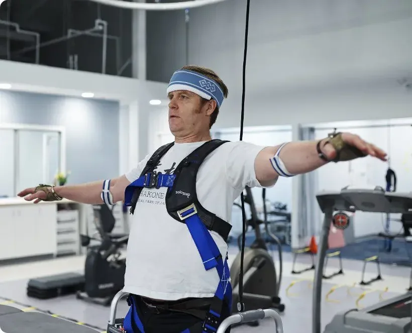 Diverse patients using solo-step fall protection system during physical therapy in modern rehab center