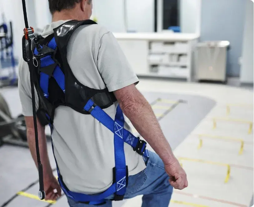 patient confidently walking using solo-step harness system during rehabilitation with therapist supervision