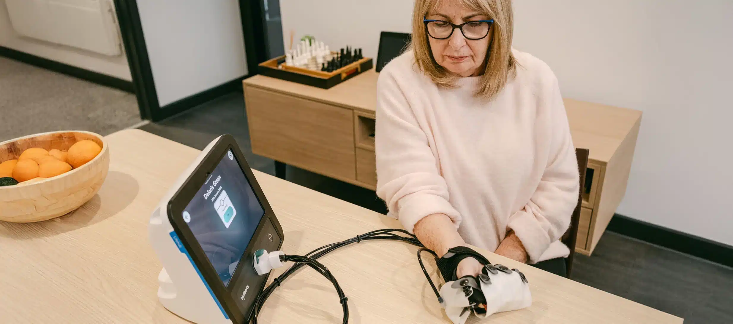 Elderly patient performing hand therapy using soft robotic glove with therapist support