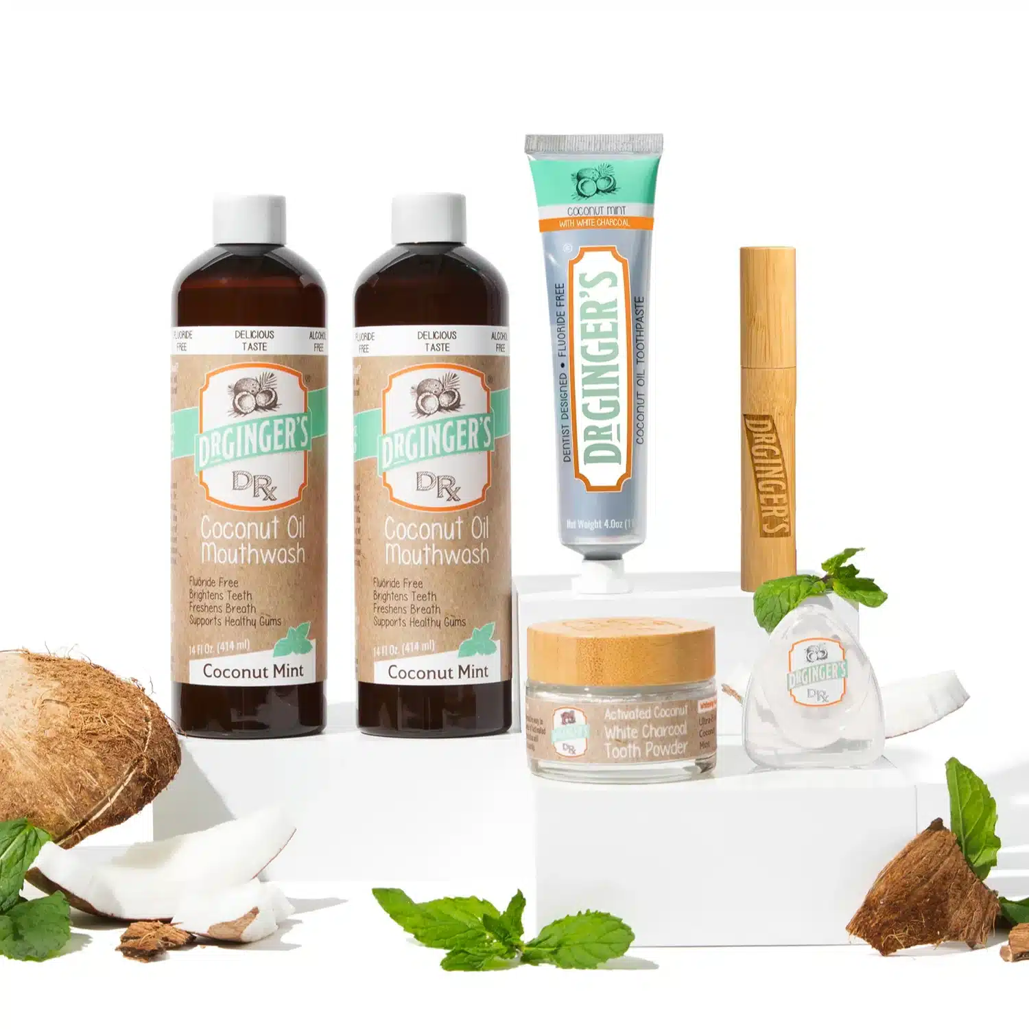 Dr. Ginger's natural oral care products including Coconut Oil Mouthwash, toothpaste, and activated charcoal tooth powder, arranged with coconut and mint leaves, highlighting innovative ingredients for enhanced dental hygiene.